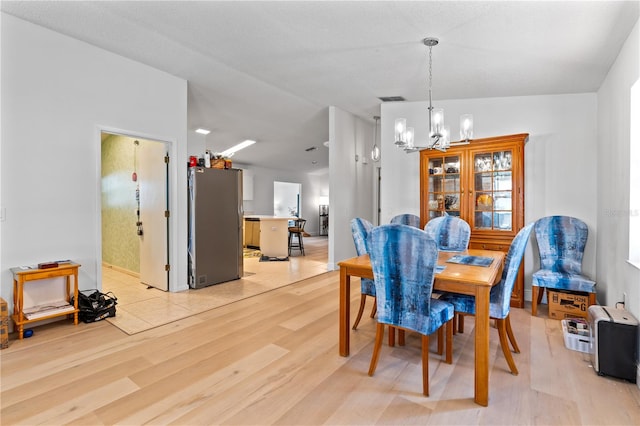 dining area with light hardwood / wood-style flooring and a notable chandelier