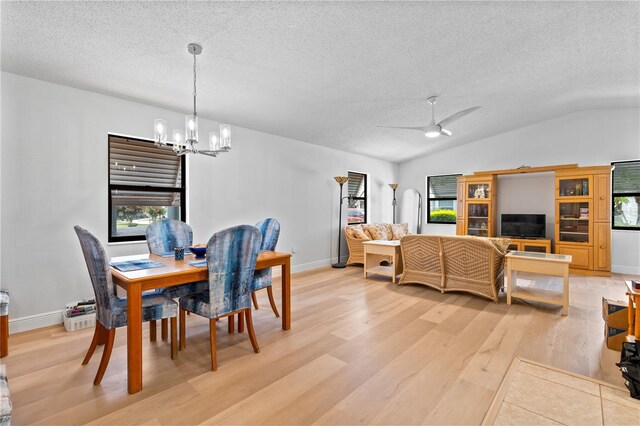 dining room with ceiling fan with notable chandelier, lofted ceiling, light hardwood / wood-style flooring, and a textured ceiling