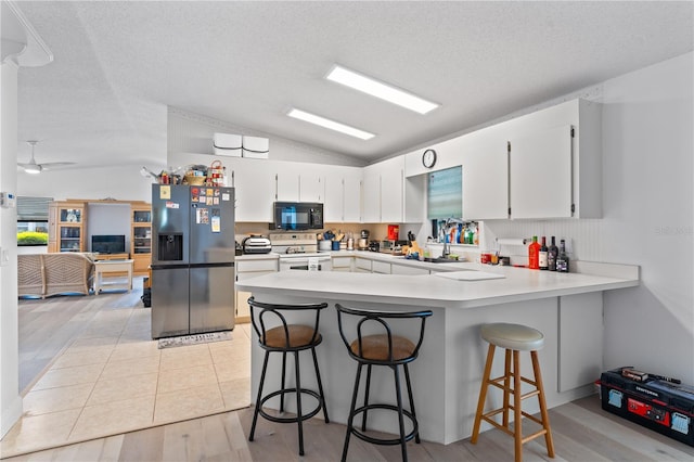 1967 Long Boat Dr, Lakeland, FL 33810 - kitchen with black microwave, a peninsula, lofted ceiling, white electric range oven, and fridge with ice dispenser