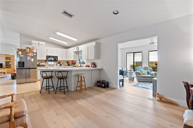 1967 Long Boat Dr, Lakeland, FL 33810 - kitchen featuring lofted ceiling, stainless steel fridge with ice dispenser, visible vents, a peninsula, and black microwave
