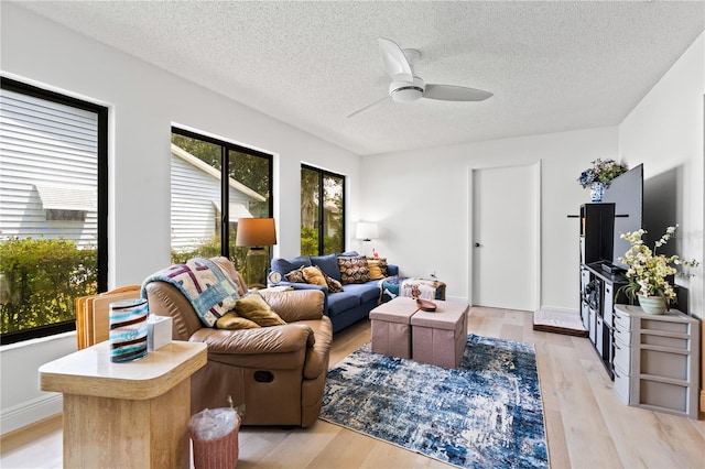 living room featuring light wood-type flooring, a textured ceiling, and ceiling fan