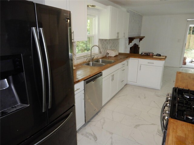 kitchen featuring black fridge with ice dispenser, decorative backsplash, dishwasher, wooden counters, and sink