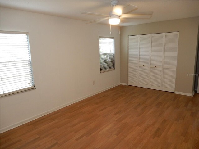 unfurnished bedroom featuring ceiling fan, a closet, and hardwood / wood-style flooring