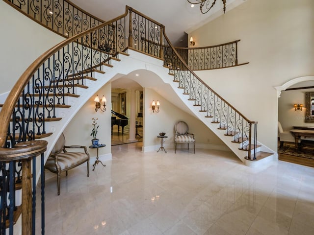 tiled entryway featuring a high ceiling and a notable chandelier