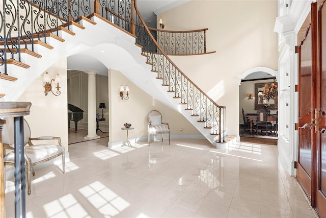 foyer entrance with tile patterned flooring, a high ceiling, and ornate columns