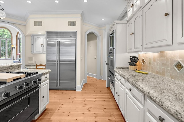 kitchen with light hardwood / wood-style flooring, white cabinetry, high quality appliances, tasteful backsplash, and ornamental molding