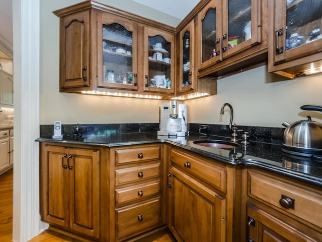 kitchen featuring dark stone countertops, sink, and light hardwood / wood-style floors