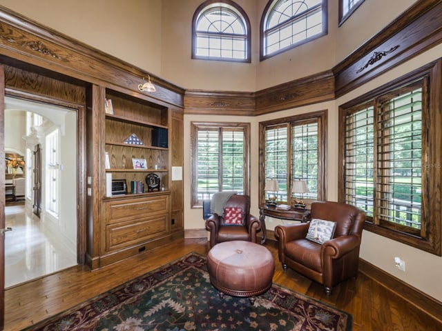 sitting room with built in shelves, a high ceiling, and dark hardwood / wood-style flooring