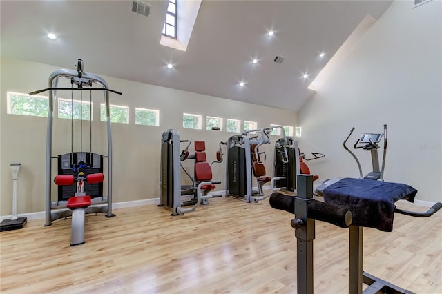 exercise area with light wood-type flooring and high vaulted ceiling