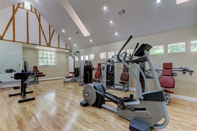 workout area featuring light wood-type flooring and high vaulted ceiling