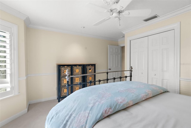 bedroom with ornamental molding, ceiling fan, light colored carpet, and a closet