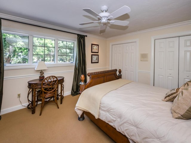 carpeted bedroom featuring ornamental molding, two closets, and ceiling fan