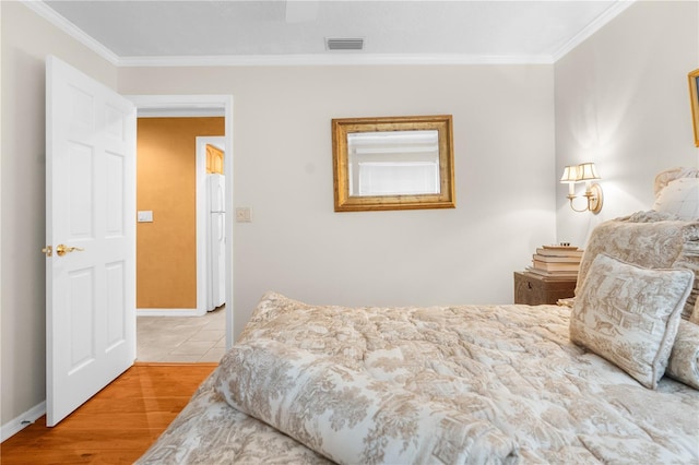 2901 Leprechaun Ln, Palm Harbor, FL 34683 - bedroom with visible vents, freestanding refrigerator, crown molding, wood finished floors, and baseboards