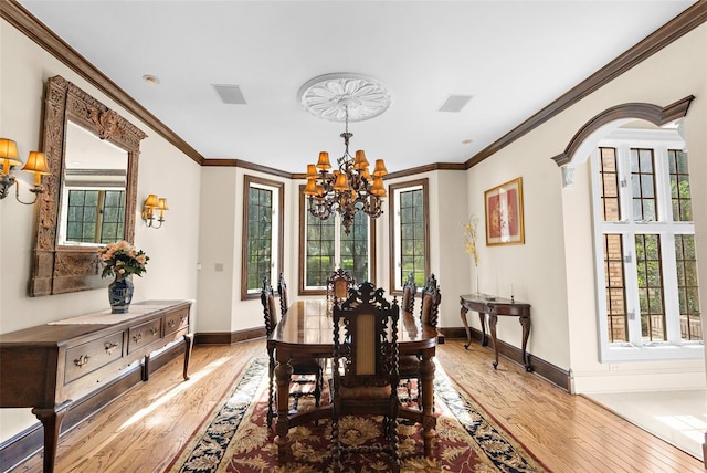 dining space with ornamental molding, plenty of natural light, an inviting chandelier, and light hardwood / wood-style floors