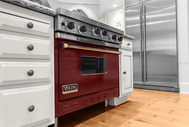 2901 Leprechaun Ln, Palm Harbor, FL 34683 - room details with white cabinets, stove, light wood-style flooring, high end refrigerator, and wall oven