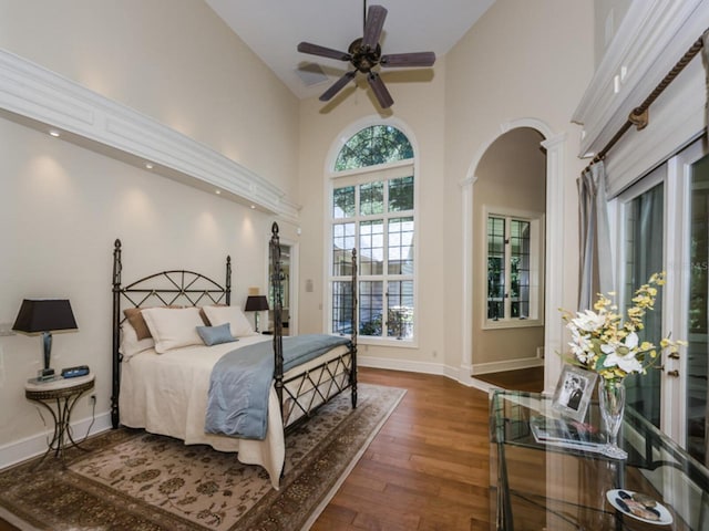 bedroom with ceiling fan, dark hardwood / wood-style flooring, and a towering ceiling