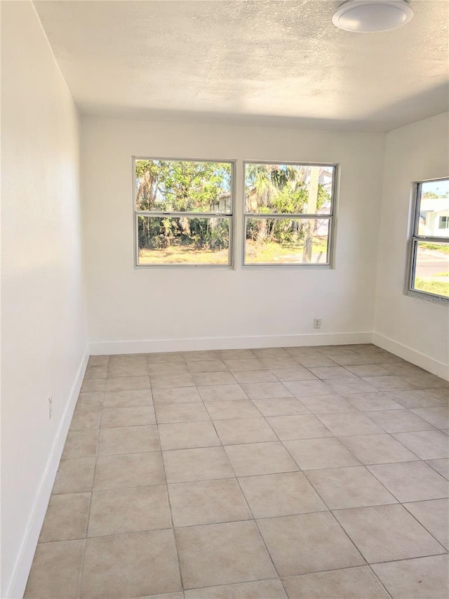 empty room with light tile patterned flooring and a textured ceiling