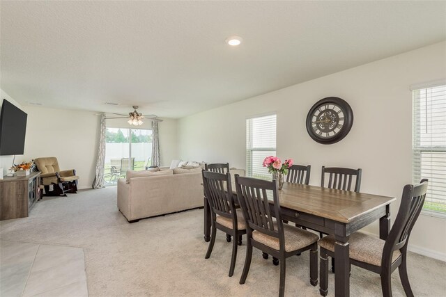 dining area with ceiling fan and light colored carpet