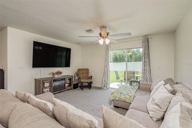 carpeted living room with ceiling fan and a textured ceiling