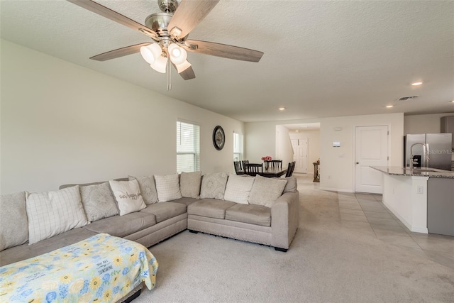 living room featuring a textured ceiling, light tile patterned floors, and ceiling fan