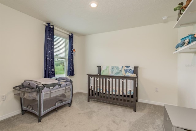 carpeted bedroom with a textured ceiling and a nursery area