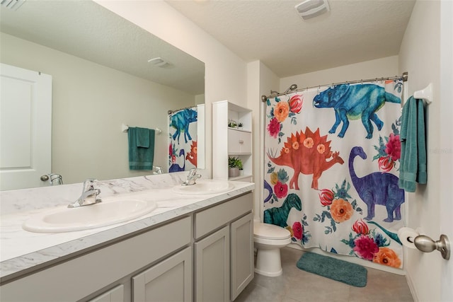 bathroom featuring double sink vanity, a textured ceiling, tile patterned floors, and toilet