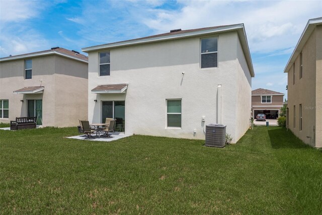 back of house featuring a lawn, central air condition unit, and a patio