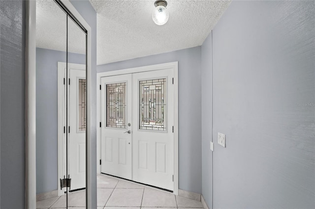 entryway with light tile patterned floors and a textured ceiling