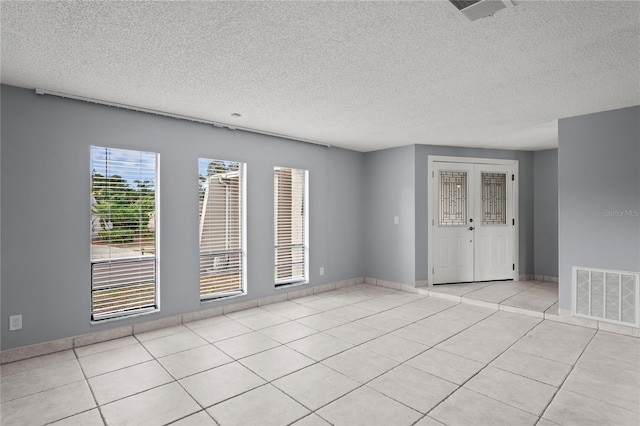 tiled empty room featuring french doors and a textured ceiling