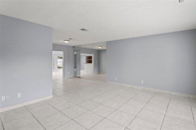 spare room with light tile patterned floors and a textured ceiling