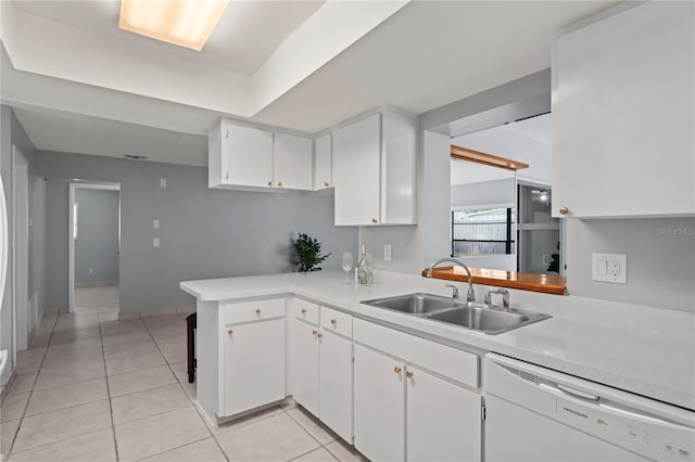 kitchen with kitchen peninsula, white dishwasher, sink, light tile patterned floors, and white cabinets