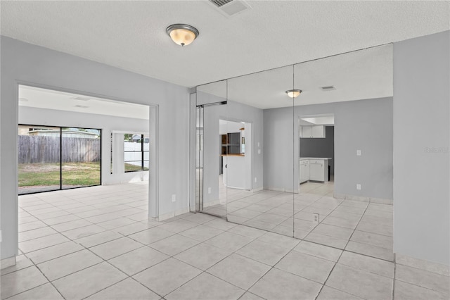 tiled empty room with a textured ceiling