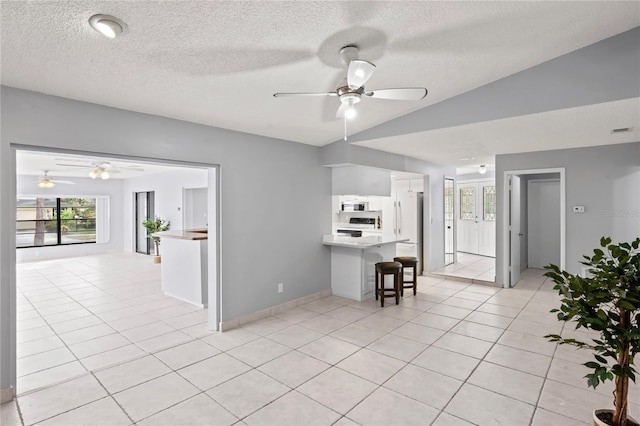 kitchen featuring light tile patterned floors, a textured ceiling, ceiling fan, and a breakfast bar area