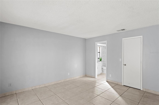 tiled spare room featuring a textured ceiling