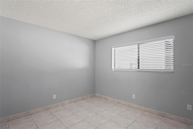 tiled empty room with a textured ceiling