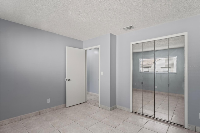 unfurnished bedroom with light tile patterned floors, a textured ceiling, and a closet