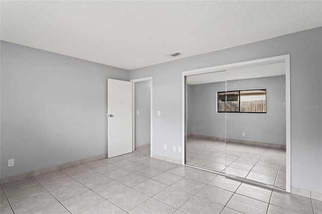 unfurnished bedroom featuring a closet, light tile patterned floors, and a textured ceiling