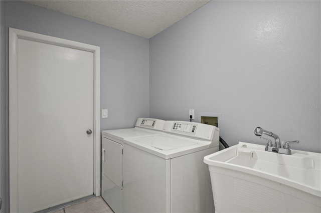 laundry room with washer and clothes dryer, sink, and a textured ceiling