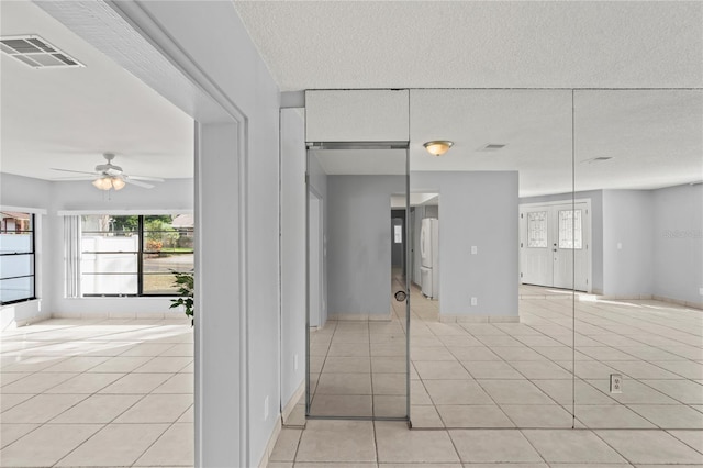 unfurnished room featuring ceiling fan, french doors, light tile patterned floors, and a textured ceiling