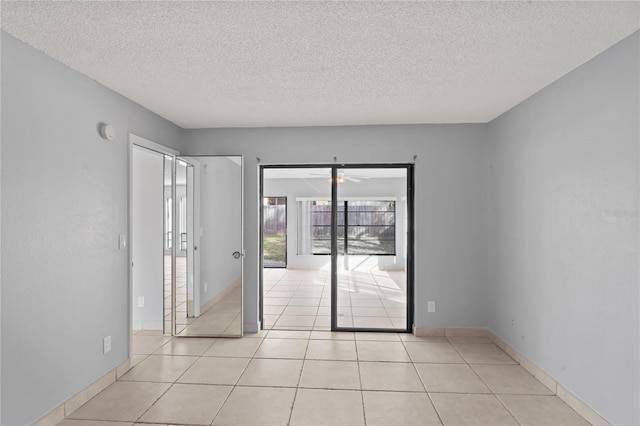 tiled spare room with ceiling fan and a textured ceiling