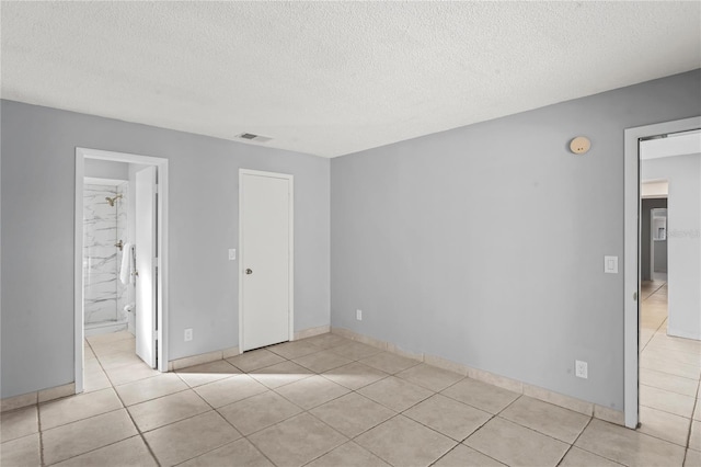 tiled empty room with a textured ceiling