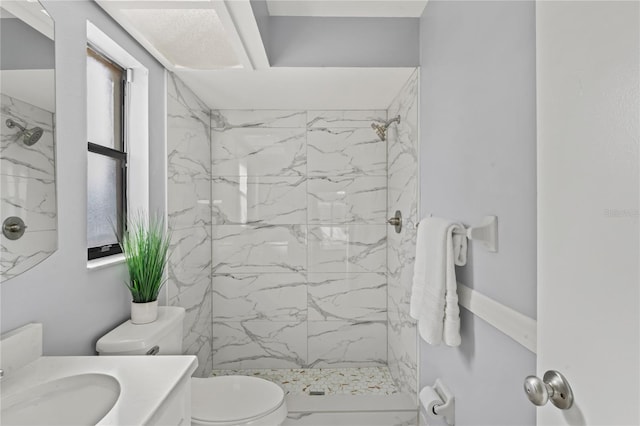 bathroom featuring tiled shower, vanity, and toilet