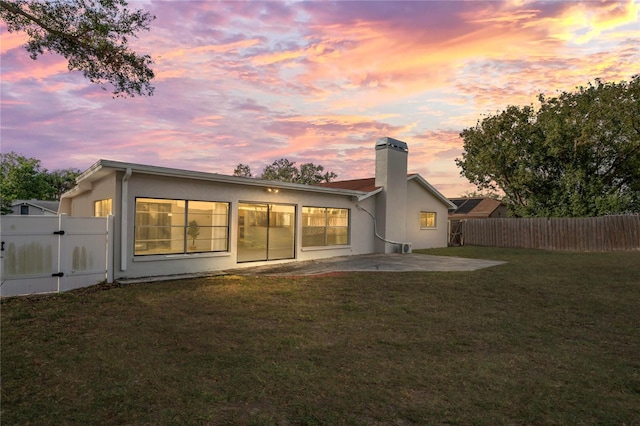 back house at dusk featuring a patio area and a yard