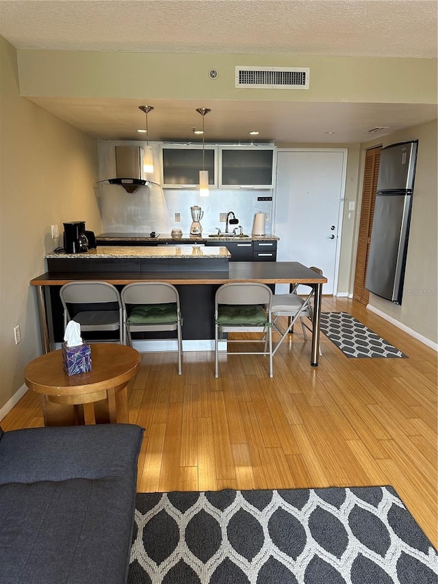 kitchen featuring decorative backsplash, pendant lighting, hardwood / wood-style flooring, and stainless steel fridge