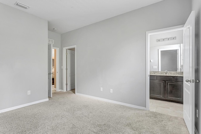 unfurnished bedroom featuring ensuite bath, sink, and light colored carpet