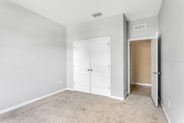 unfurnished bedroom with light colored carpet and a closet