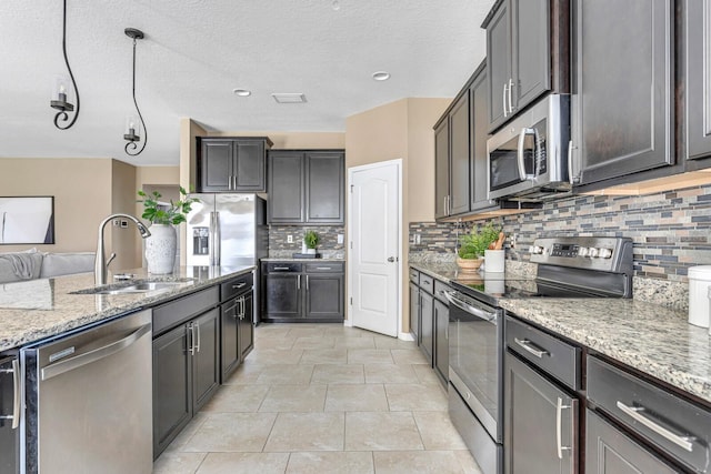 kitchen featuring decorative backsplash, stainless steel appliances, light stone countertops, and sink