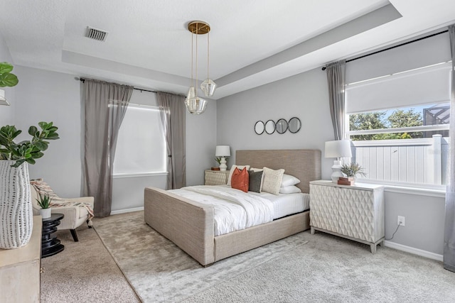 carpeted bedroom with a textured ceiling and a tray ceiling