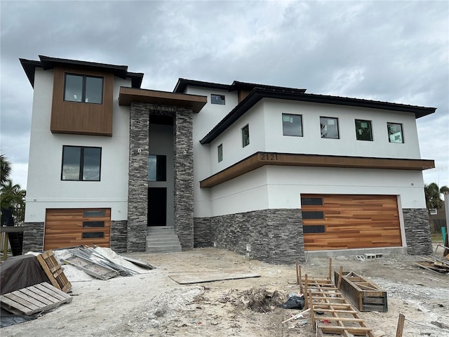 contemporary home with entry steps, stone siding, and stucco siding