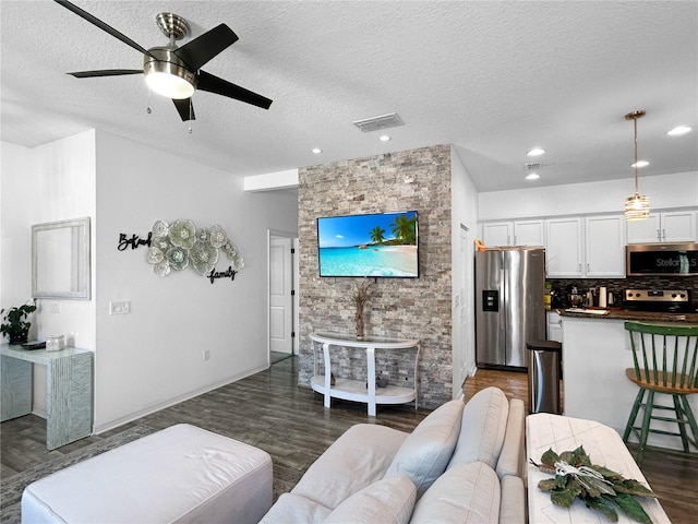 living room featuring ceiling fan, a textured ceiling, and dark hardwood / wood-style floors